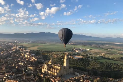 Globo aerostático flotando sobre la catedral de Segovia con vistas a la campiña rural castellana y montañas