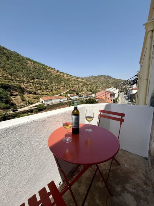 Balcony terrace with wine glasses at Casa Tawny B&B in Pinhão, Portugal, overlooking terraced vineyard hills