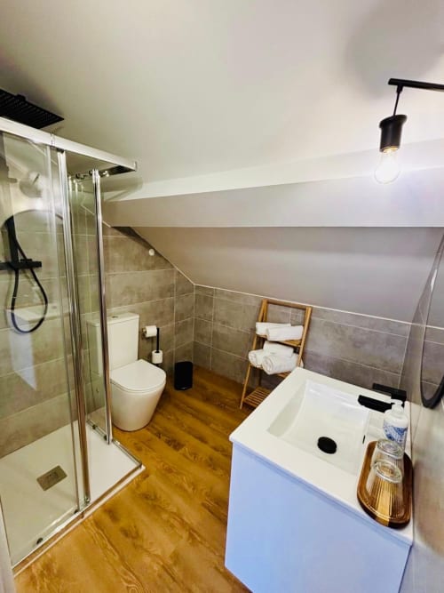 Modern ensuite bathroom at Casa Tawny with shower, sink, toilet, wooden floor and heated towel rack in Pinhão