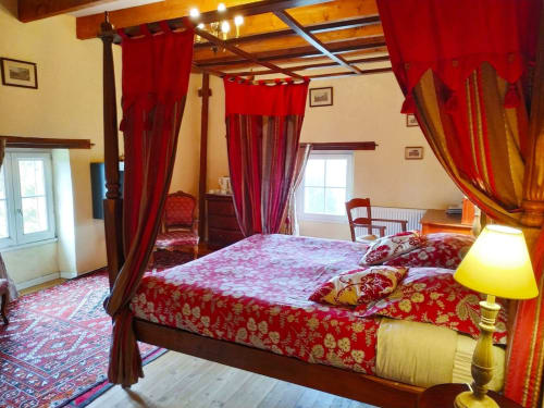 Lit à baldaquin élégant aux draperies rouges et parure florale dans la chambre Duplex de la Tour du Château de Bellevue