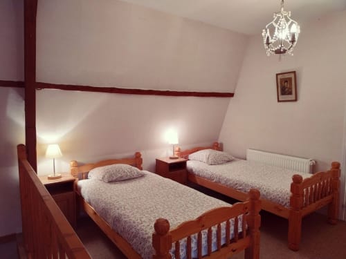 Lits jumeaux aux cadres en bois dans la chambre Duplex de la Tour du Château de Bellevue, un gîte français au mobilier élégant