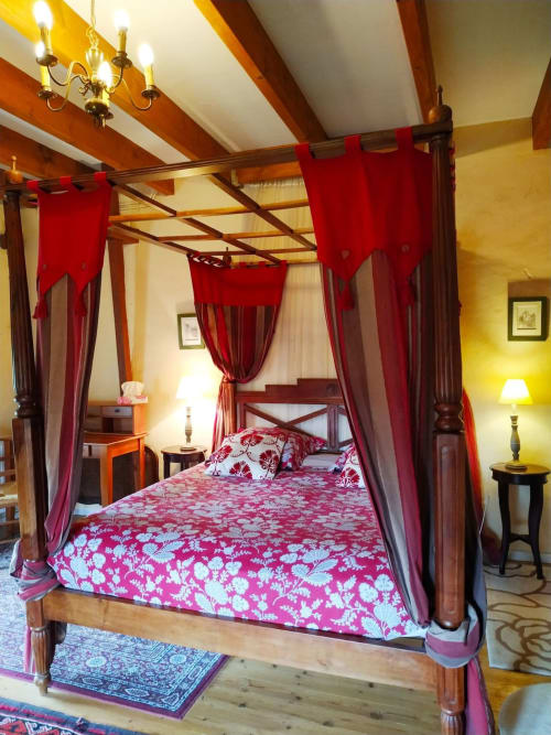 Chambre d'hôtes de charme près du Puy du Fou. Lit à baldaquin luxueux avec tentures rouges dans la chambre Duplex de la Tour du Château de Bellevue
