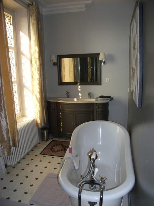 Salle de bains élégante de la Suite du Maréchal au Château de Bellevue avec baignoire indépendante, double vasque et lumière naturelle