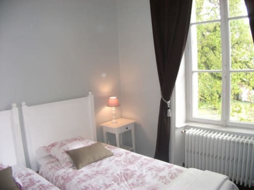 Chambre Suite du Maréchal au Château de Bellevue avec literie toile rose, vue sur jardin et lampe de lecture
