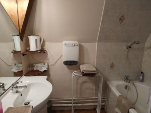 Salle de bains au Château de Bellevue avec lavabo blanc, baignoire, radiateur mural et équipements à Sainte-Cécile