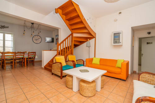 Salon lumineux à Vacances en Touraine avec escalier orange, canapé orange et carrelage en terre cuite