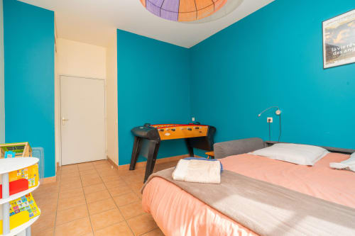 Chambre d'enfants colorée avec murs turquoise, baby-foot et lits jumeaux à Vacances en Touraine