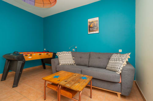 Salle de jeux avec baby-foot, jeu de cornhole, canapé gris et murs turquoise à Vacances en Touraine, Souvigny-de-Touraine