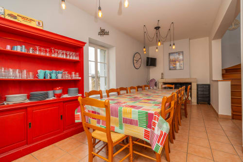 Salle à manger lumineuse à Vacances en Touraine avec table colorée, chaises orange et élégantes armoires rouges