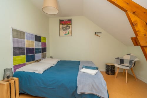 Chambre mansardée moderne aux Vacances en Touraine avec tête de lit colorée, literie bleue, poutres bois et style contemporain