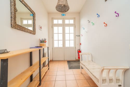 Couloir lumineux à Vacances en Touraine avec bureau en bois, décor mural coloré et lit bébé crème à Souvigny-de-Touraine