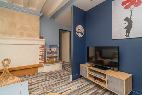 Mur d'accent bleu moderne avec TV, cheminée, art arboré et jouets d'enfant dans la suite Vacances en Touraine