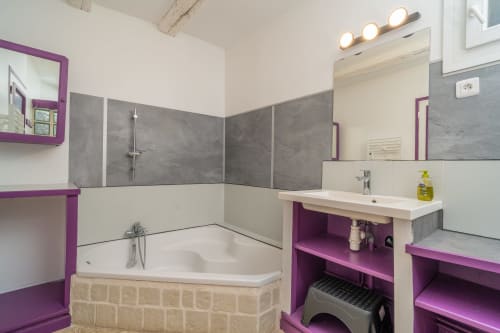 Salle de bain moderne aux Vacances en Touraine avec accents violets, double vasque, baignoire et carrelage gris