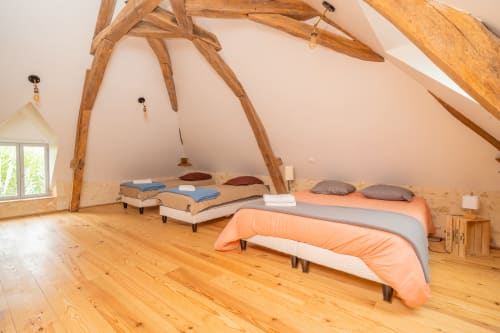 Dortoir rustique avec poutres apparentes, lits multiples aux draps colorés à Vacances en Touraine, Souvigny-de-Touraine