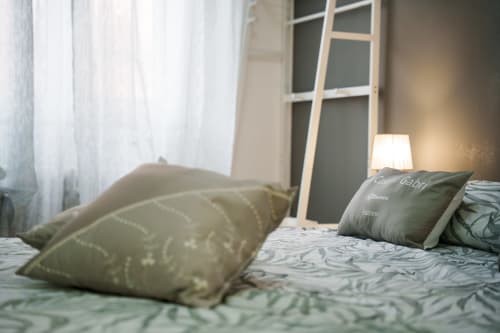 Modern bedroom at Navigli Affittacamere in Rozzano with green patterned bedding, pillows, and ambient lamp lighting