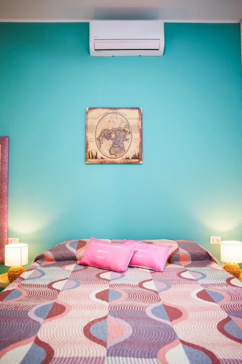 Colorful bedroom at Navigli Affittacamere in Rozzano with turquoise walls, patterned bedding, and vintage map artwork