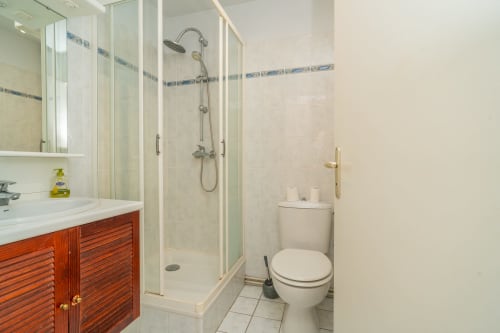 Salle de bain moderne avec meuble-lavabo en bois, douche vitrée et carrelage bleu à Vacances en Touraine