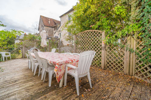 Terrasse de restauration en plein air à Vacances en Touraine avec chaises blanches, nappe rouge, clôture à treillis et murs couverts de lierre