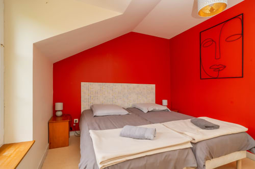 Chambre moderne du gîte Le Chêne à Souvigny-de-Touraine avec murs rouges vifs et lits jumeaux
