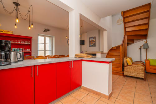 Cuisine rouge et blanche lumineuse avec escalier en bois au gîte Le Chêne, Vacances en Touraine, Souvigny-de-Touraine