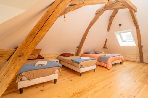 Chambre mansardée rustique avec poutres apparentes, plusieurs lits et puits de lumière au gîte Vacances en Touraine