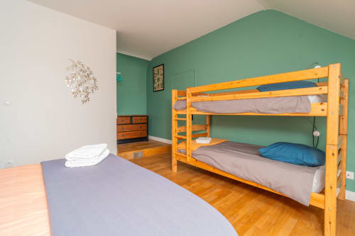 Chambre du gîte Vacances en Touraine à Souvigny-de-Touraine avec lit superposé en bois, lit simple, commode et murs verts.