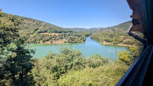 Lago turchese circondato da verdi colline e foreste alle Cabane e lodge del Belvédère a Serrières-sur-Ain