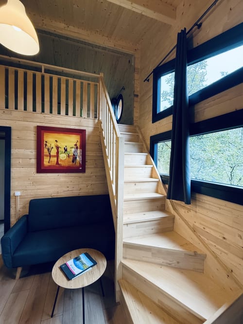 Interno di lodge in legno con scale, area relax blu navy e arte incorniciata alle Cabanes du Belvédère, Serrières-sur-Ain