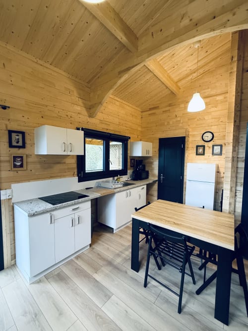Cucina e sala da pranzo moderna nel Lodge l'EPERVIER con mobili bianchi, soffitti in legno e tavolo da pranzo nero alle Cabanes
