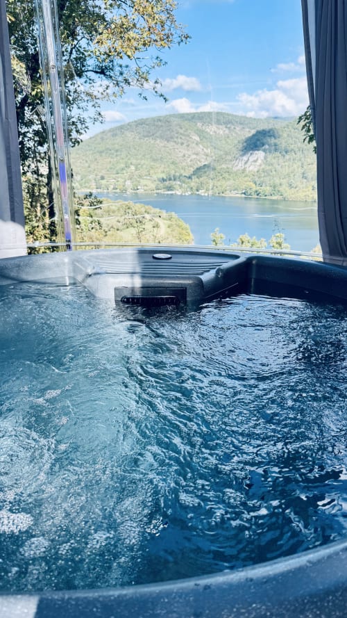 Luxury spa tub with panoramic lake and mountain views at Cabanes du Belvédère lodge in Serrières-sur-Ain