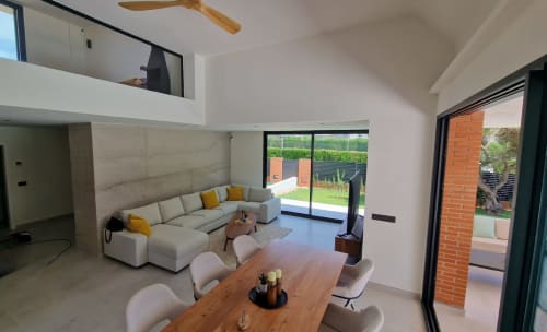 Salón moderno de villa en Benicàssim con sofá seccional, mesa de comedor y vistas al jardín a través de grandes ventanales