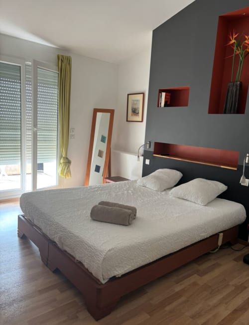 Modern bedroom with queen bed, gray and red décor, sliding glass doors at La Conciergerie De Franck villa in Boissières