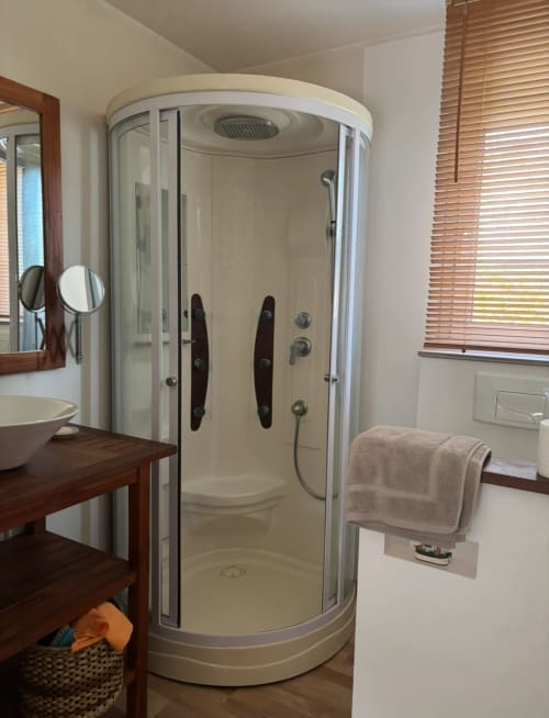 Modern curved glass shower enclosure with black handles in villa bathroom at La Conciergerie De Franck, Boissieres