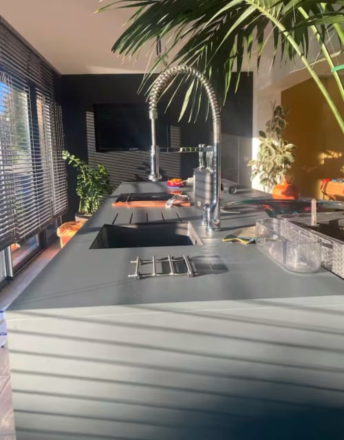 Modern kitchen with dark countertops, stainless steel faucet, and green plants at La Conciergerie De Franck villa in
