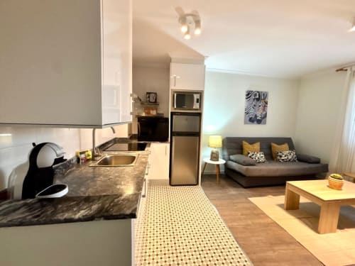 Apartamento Holibai en Baiona: moderno salón abierto con cocina, comedor y sofá con vistas a la ciudad
