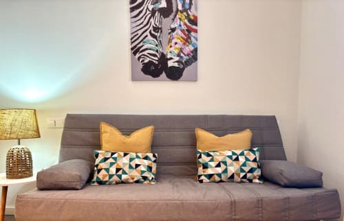 Sofá tapizado gris con cojines amarillos y estampados en el apartamento Xacobe de Holibai, Baiona