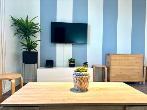 Sala moderna del apartamento Xacobe en Baiona, con paredes azules a rayas, TV montada en pared, muebles de madera y plantas en macetas