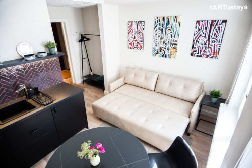 Stylish studio overview with Ralf Sannikov artworks, dining & sleeping area. Perfect Tartu accommodation near Town Hall Square. Walk to RIMI & MyFitness. WiFi & AC