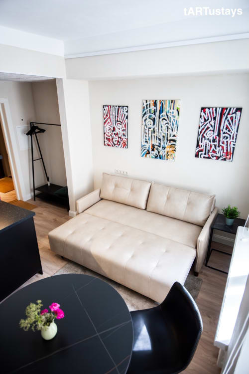 Comfortable sofa bed with Ralf Sannikov's art collection on display. Cozy Tartu studio near Town Hall Square, walking distance to RIMI & MyFitness