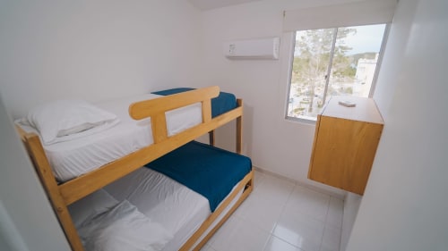 Dormitorio luminoso con camas literas de madera en hotel Olamar Living, Coveñas, Colombia, con aire acondicionado y vistas al jardín
