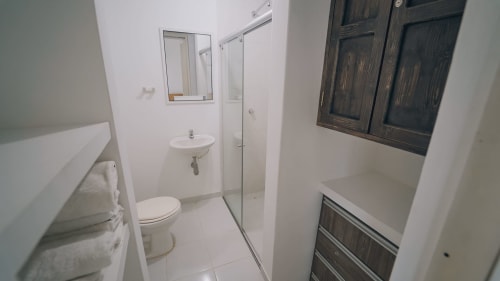 Baño moderno en Olamar Living Coveñas con paredes blancas, inodoro, lavamanos, espejo y ducha con mampara de vidrio