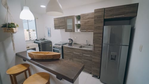 Cocina moderna con gabinetes de madera oscura, electrodomésticos de acero inoxidable y barra en apartamento Olamar Living Coveñas