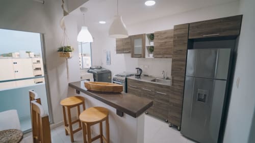 Apartamento cocina moderna en Olamar Living Coveñas con gabinetes de madera, electrodomésticos de acero inoxidable, barra desayunadora y vista al océano