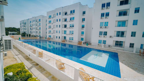 Moderno complejo residencial blanco con piscina de azulejos azules y tumbonas en el hotel Olamar Living de Santiago de Tolú