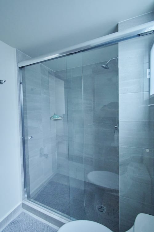 Moderna mampara de ducha de vidrio en apartamento de Pares Homes Ciudad de México con diseño de baño contemporáneo