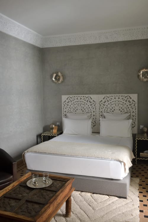 Elegant slaapkamer in Riad Palau Marrakech met verfraaide witte hoofdeinde, wit beddengoed, gouden wandlampen en traditionele inrichting