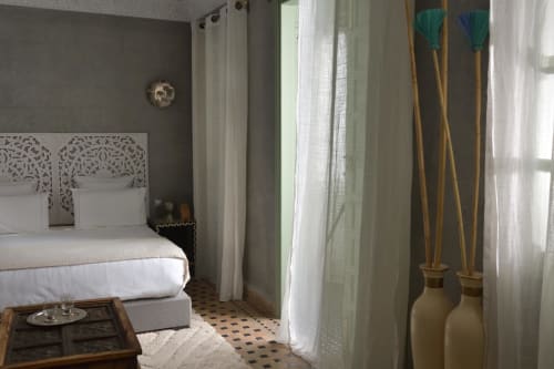Luxe slaapkamer in Riad Palau Marrakech met versierde hoofdeinde, wit beddengoed en traditionele Marokkaanse inrichting