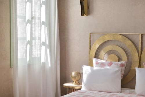 Luxueuze slaapkamer met gouden ronde hoofdeinde en roze bloemensierkussens in Riad Palau Marrakech, transparante gordijnen