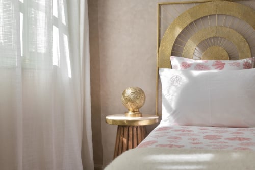 Luxe slaapkamer in Riad Palau Marrakech met gouden spiraalvormig hoofdeinde, witte lakens en sheer gordijnen bij het raam