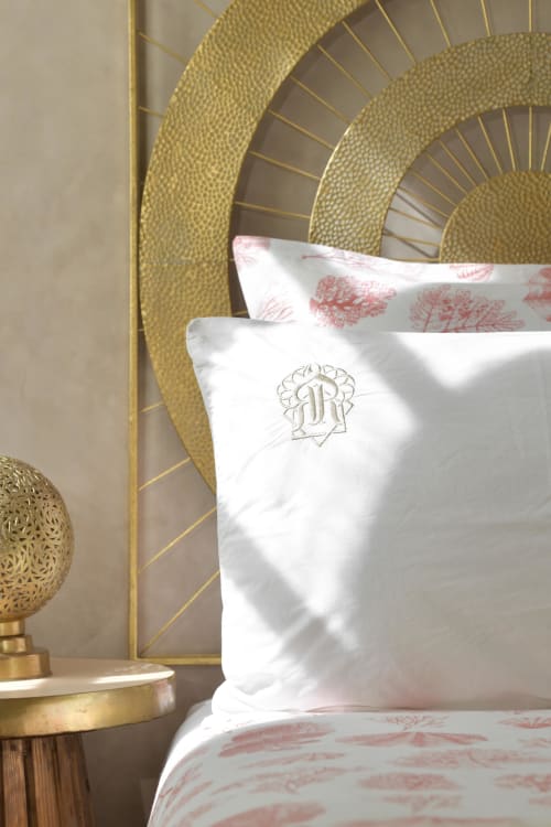 Luxe kussens met monogram in het Riad Palau Marrakech, met gouden hoofdeinde en rode toile-bedding